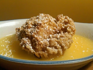 Golden fried chicken drizzled with sweet citrus sauce on a blue plate.