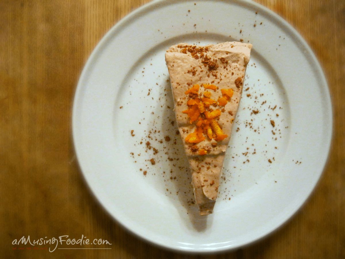 Delicious orange mousse dessert elegantly plated, garnished with crumbs, on a rustic wooden table.