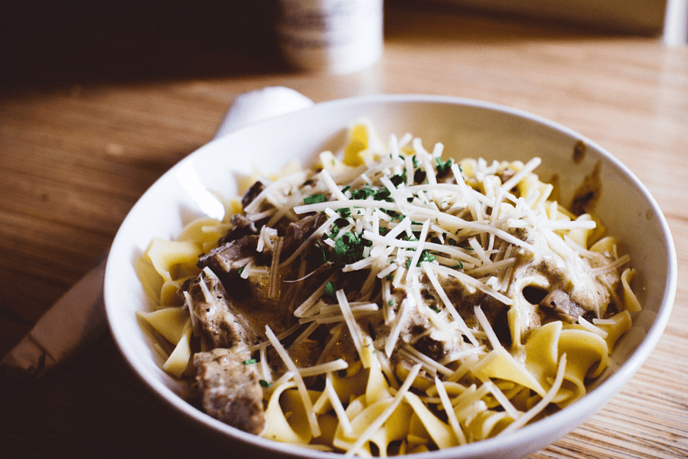 Creamy mushroom pasta topped with Parmesan cheese for a comforting and flavorful dining experience.