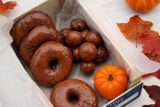 Fresh autumn donuts with pumpkin and colorful leaves create a cozy seasonal treat.