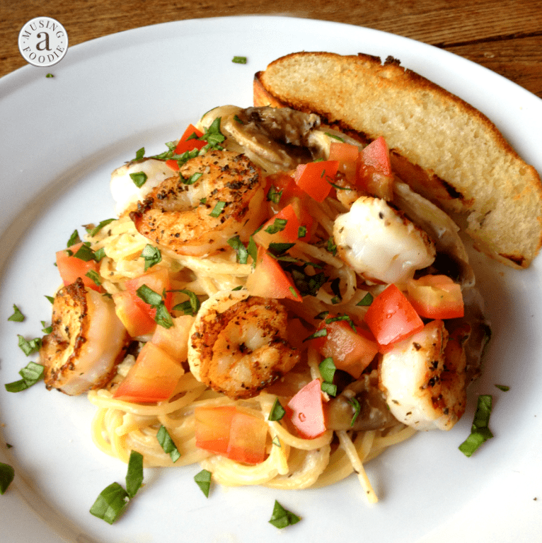 Delicious creamy garlic shrimp pasta topped with fresh tomatoes and herbs in a vibrant presentation.