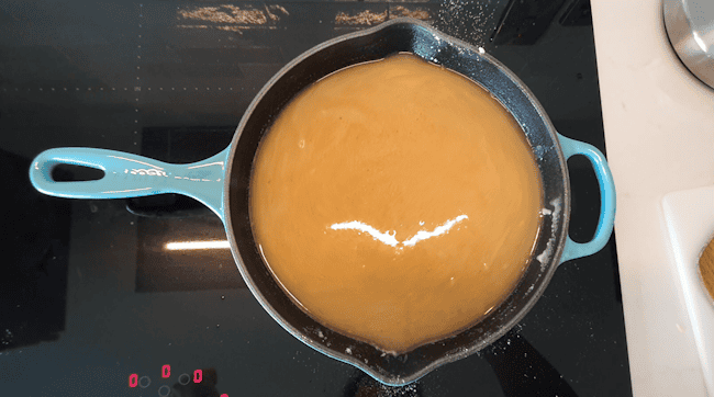 Whisking butter and flour to make a roux in a skillet.