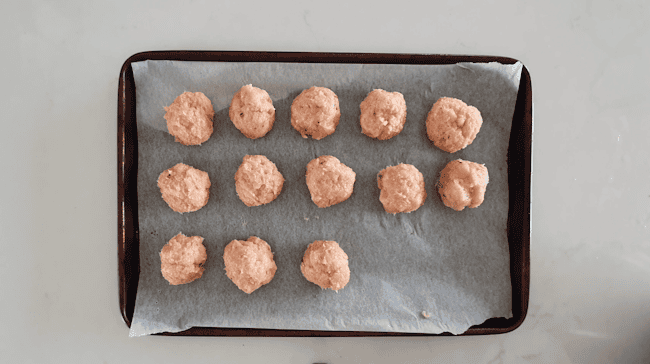 Shaped turkey meatballs on a parchment-lined sheet pan.