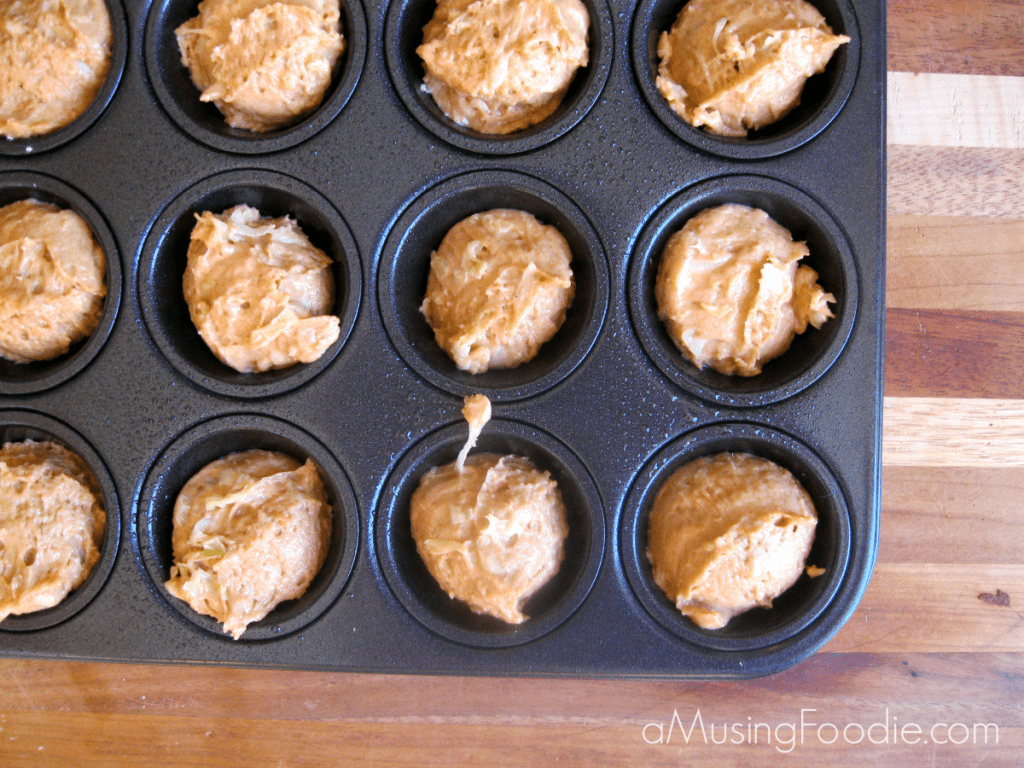 Homemade egg-free zucchini muffin batter ready for the oven in a black muffin tin.