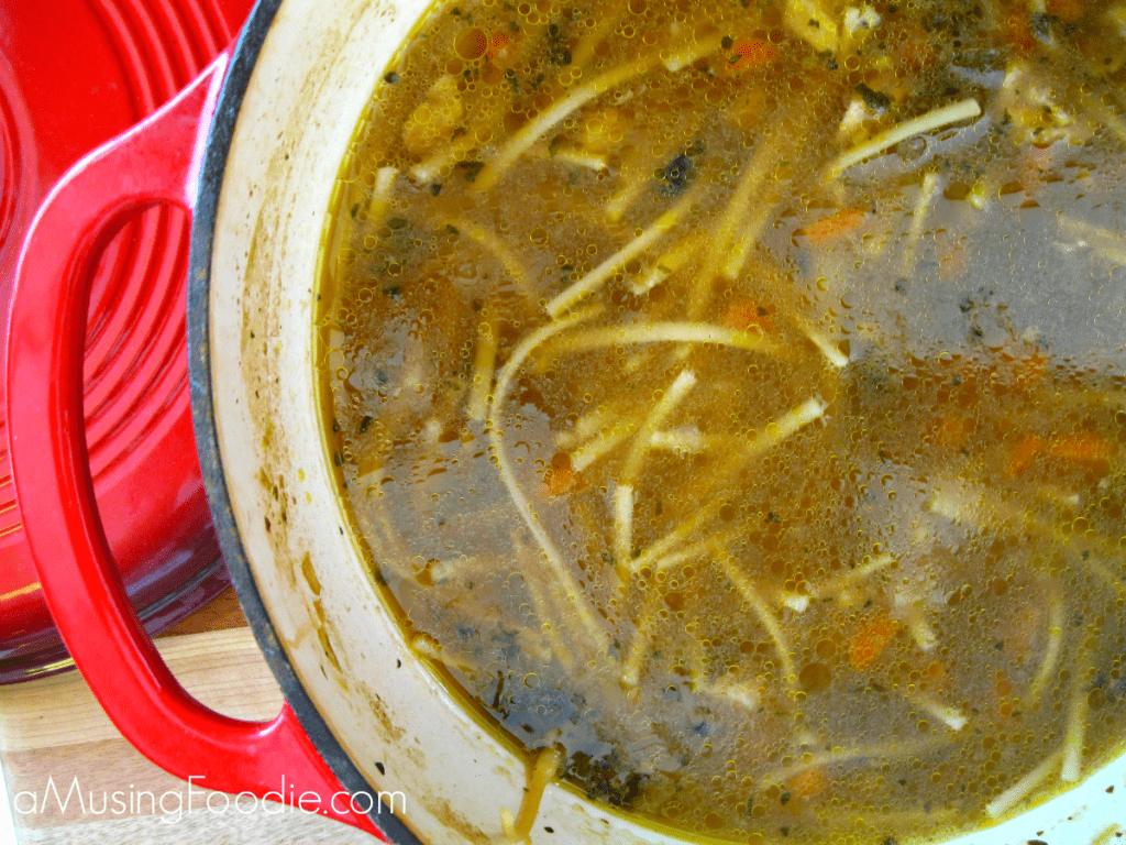 Delicious homemade chicken noodle soup simmering in a vibrant red cast iron pot.