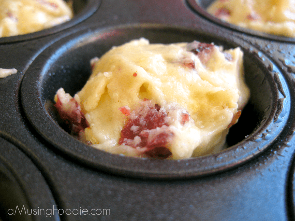 Savory muffins filled with meat and vegetables baking in a non-stick muffin tin.