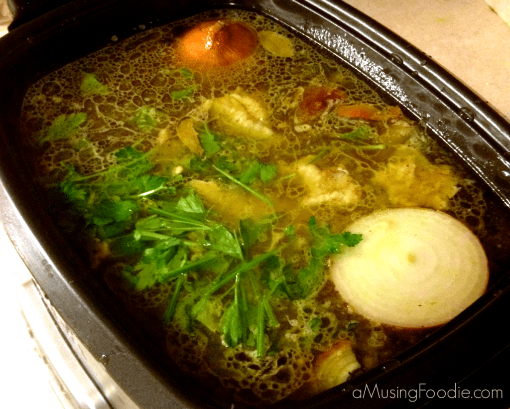 Warm, bubbling chicken soup with fresh herbs and colorful vegetables simmering in a slow cooker.