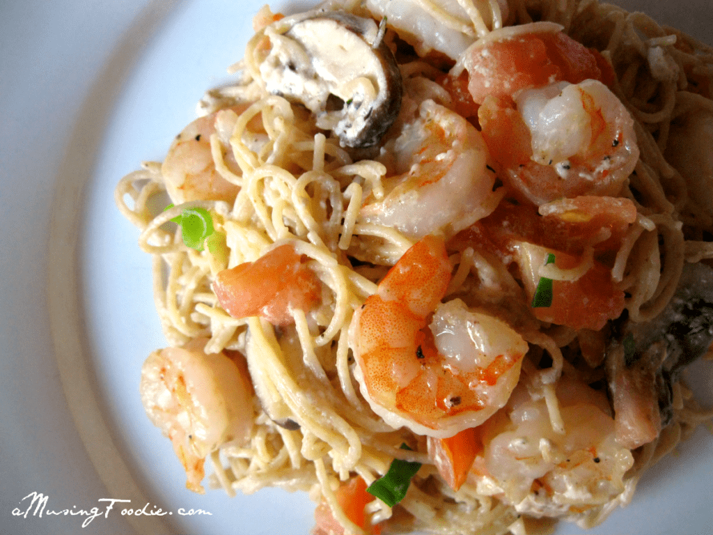 Creamy shrimp pasta topped with fresh green onions in a savory sauce.