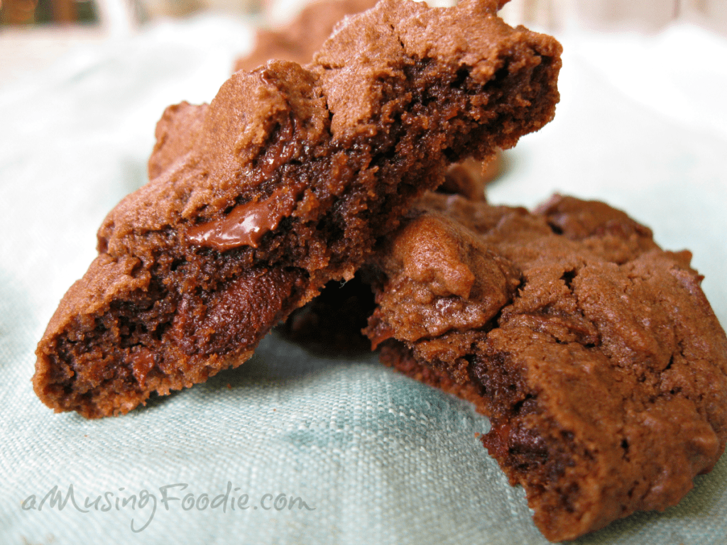Freshly baked double chocolate cookies stacked on soft blue fabric, inviting and delicious.