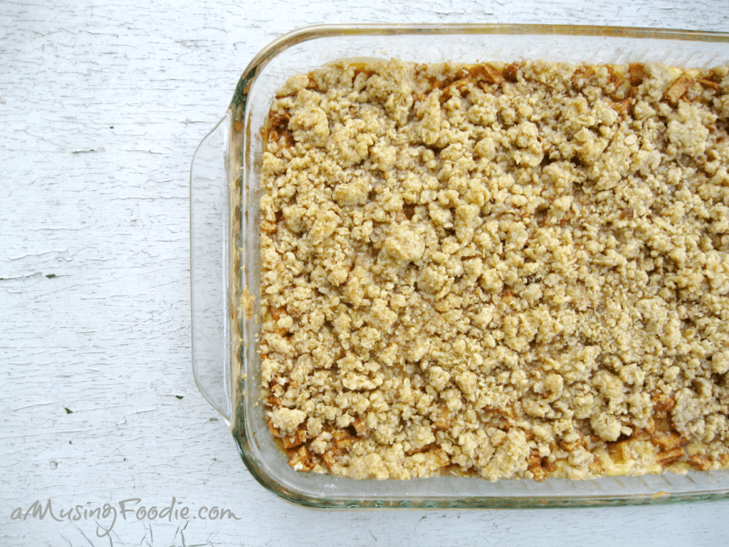 Delectable apple cinnamon crumb bars in a glass dish on a rustic wooden surface.
