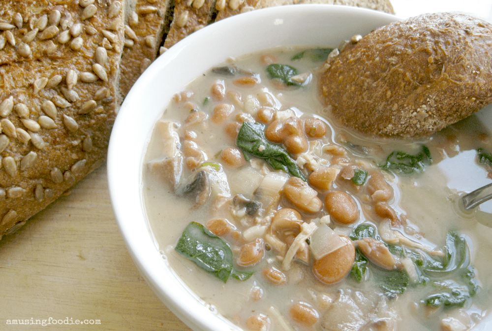 Warm chicken and pinto bean soup served with rustic bread for a cozy meal.