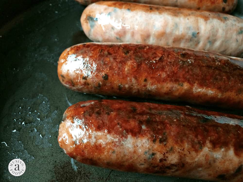 Seared chicken sausage in a skillet.