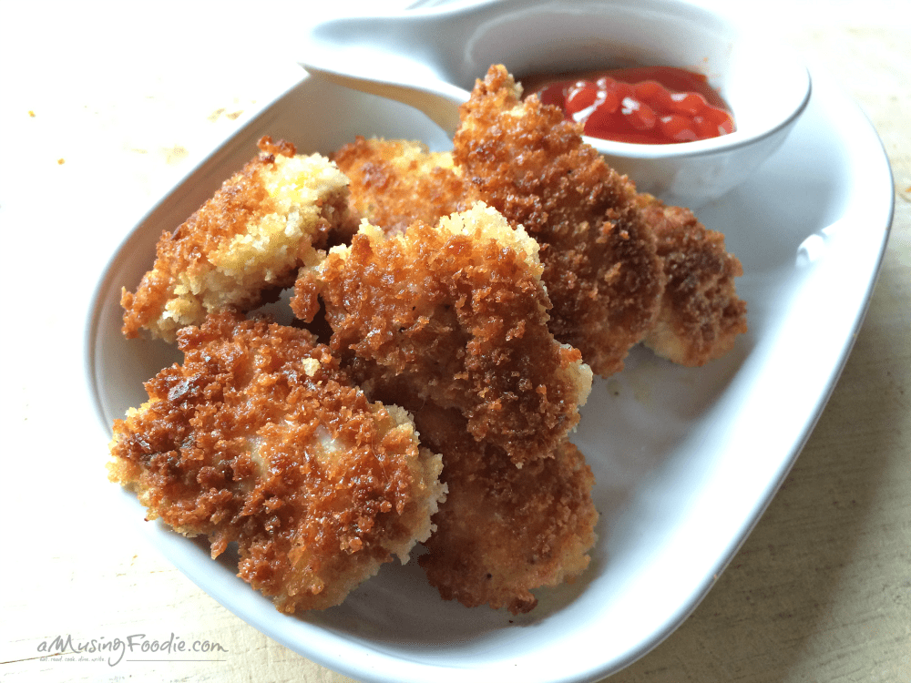 Golden crispy chicken nuggets served with a side of ketchup for dipping.