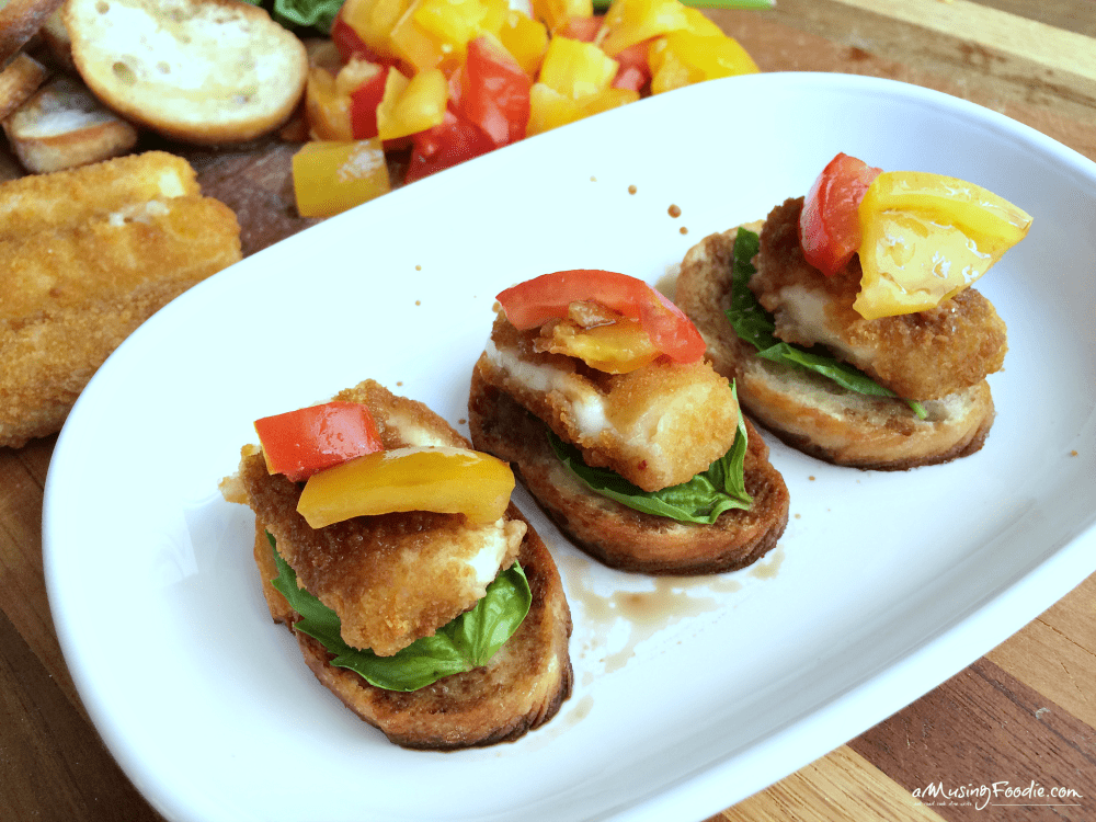 Crispy fish appetizers topped with vibrant bell peppers and tomatoes on toasted bread.