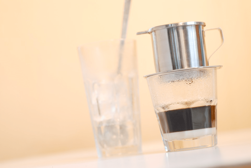 Brewing traditional Vietnamese iced coffee with a drip filter and glistening ice cubes.
