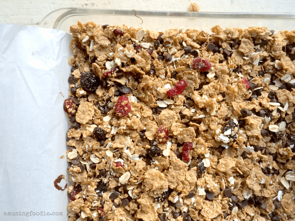 Homemade cranberry chocolate granola bars, featuring oats, chocolate, and dried fruit in a baking dish.