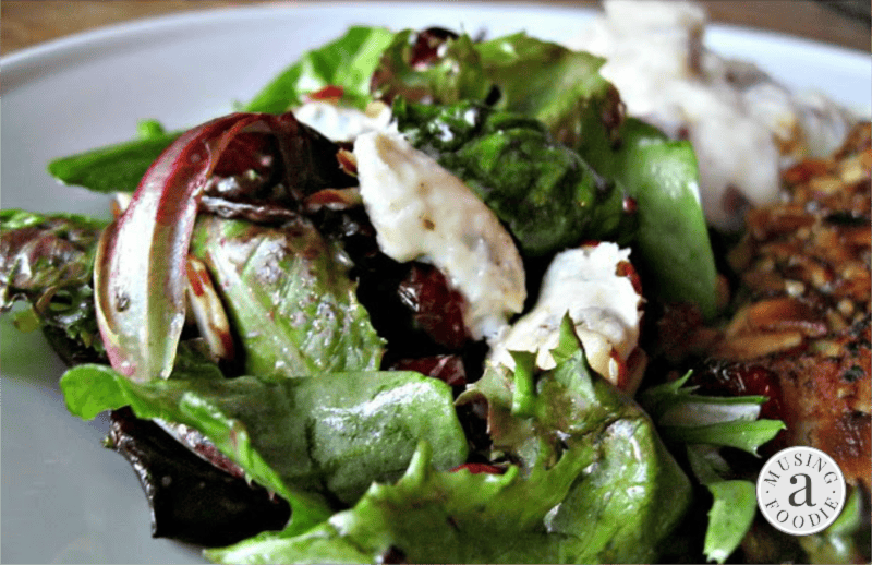 Vibrant green salad with Gorgonzola, cranberries, and almonds in a light dressing.