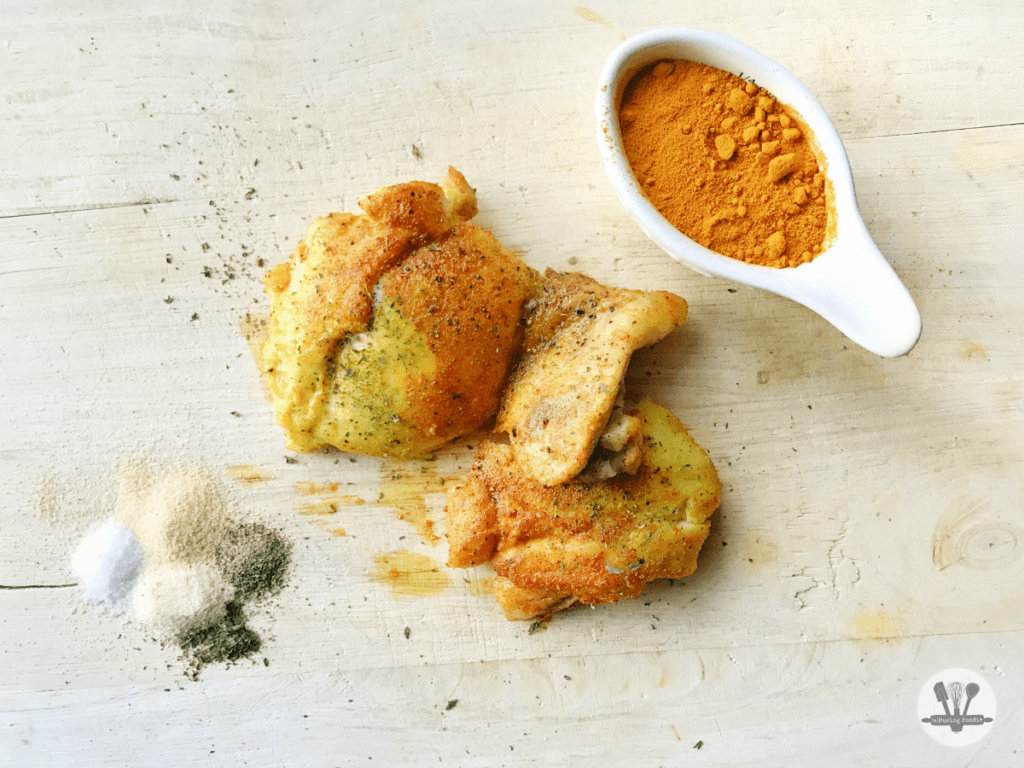 Succulent turmeric chicken thighs with spices, beautifully arranged on rustic wood for a homey feel.