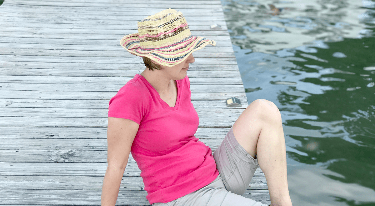 Woman enjoys a tranquil moment by the water, embracing natures beauty in summer leisure.