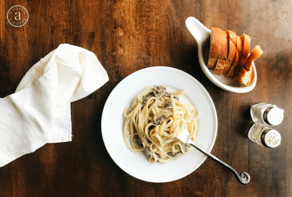 Indulge in creamy vegan fettuccine Alfredo with sautéed mushrooms and toasted bread.