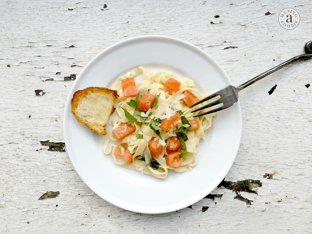 Delicious creamy tomato basil fettuccine topped with vibrant tomatoes and fresh greens.