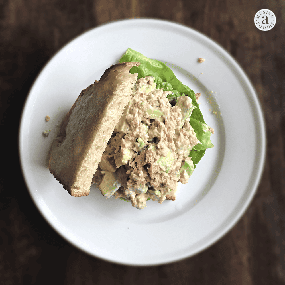 Classic whole grain tuna salad sandwich with fresh lettuce on a rustic wooden table.