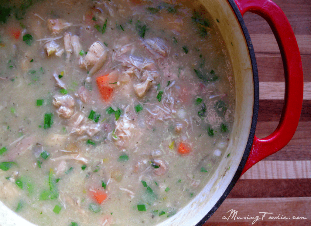 Homemade chicken soup simmering in a rustic red Dutch oven, perfect for comfort and warmth.