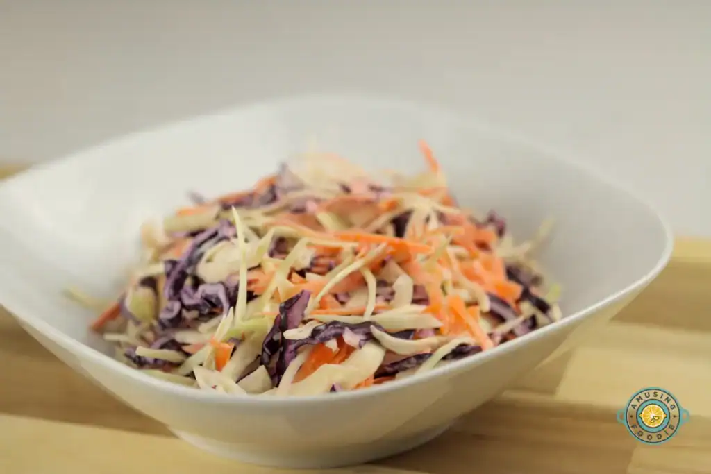 Colorful coleslaw bowl with fresh green and purple cabbage, and bright orange carrots.