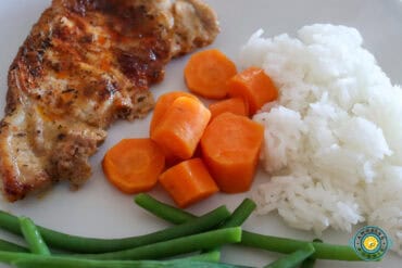 Pork chop served with rice, veggies