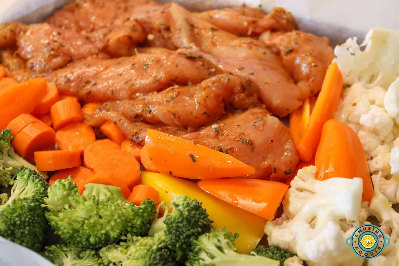 raw chicken and veggies on sheet pan