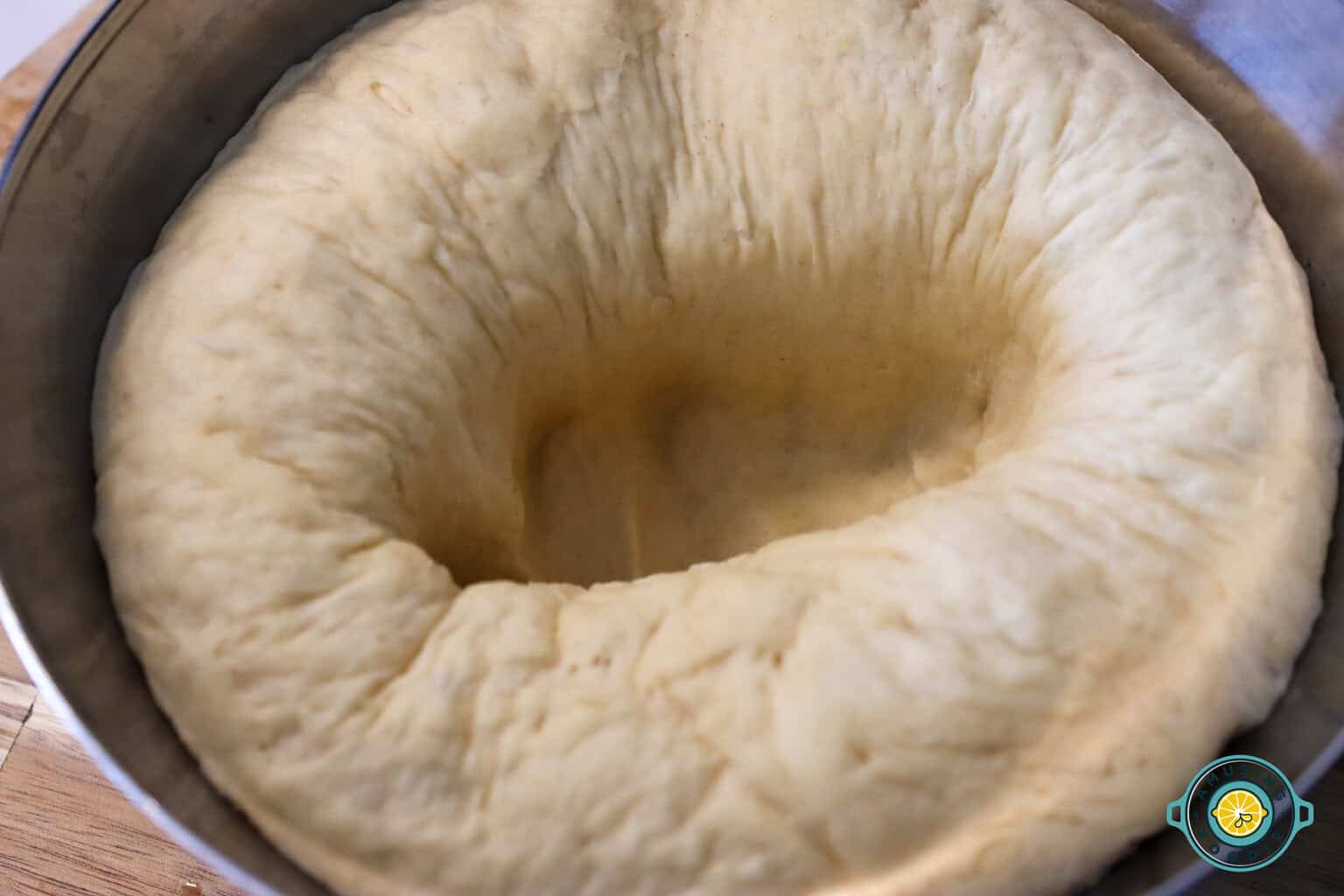 Risen bread dough in a bowl that has been punched down