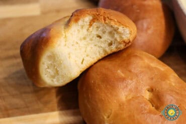 Soft golden-brown dinner roll with a bite, showing the fluffy, airy inside