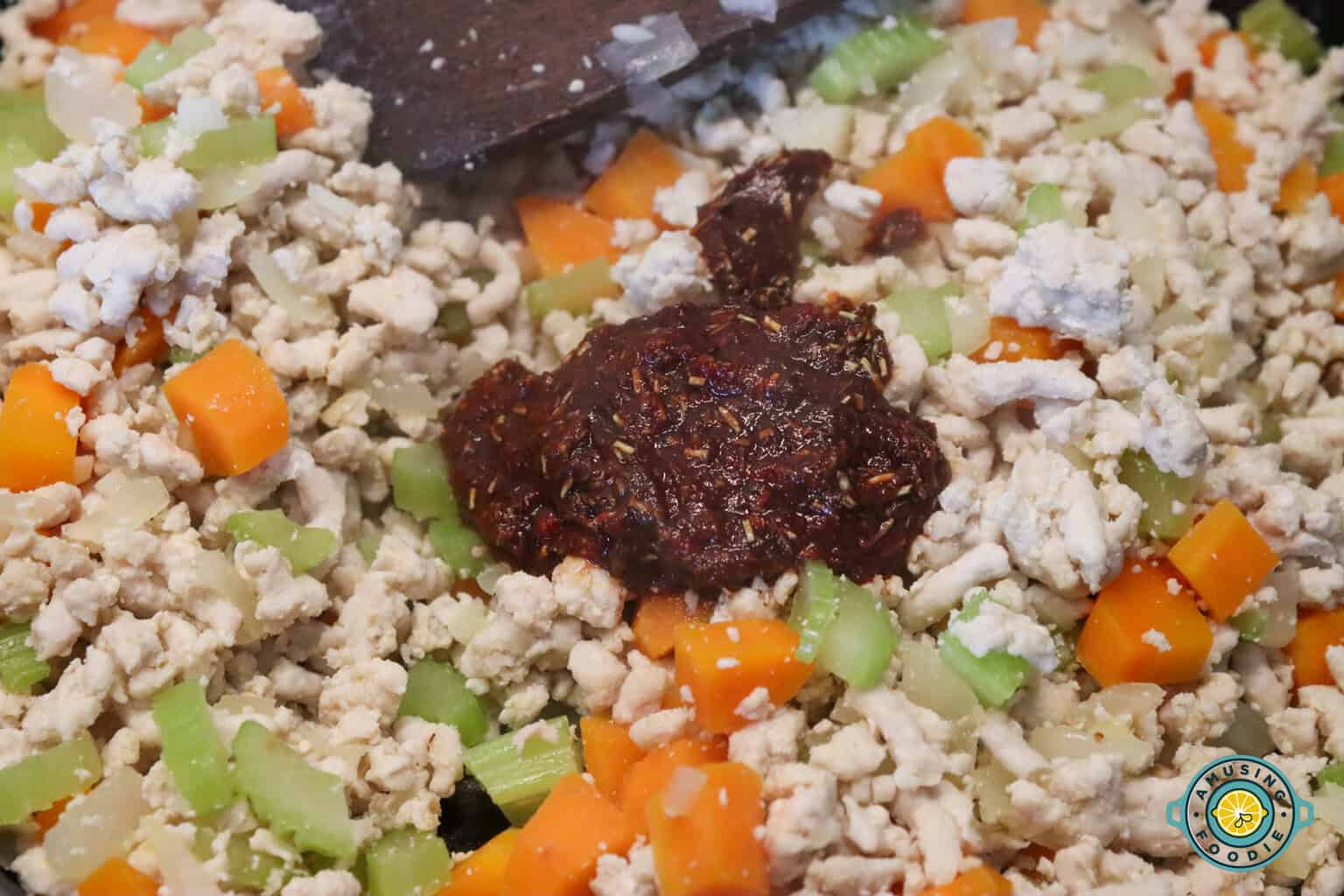 adding tomato paste mixture on ground turkey