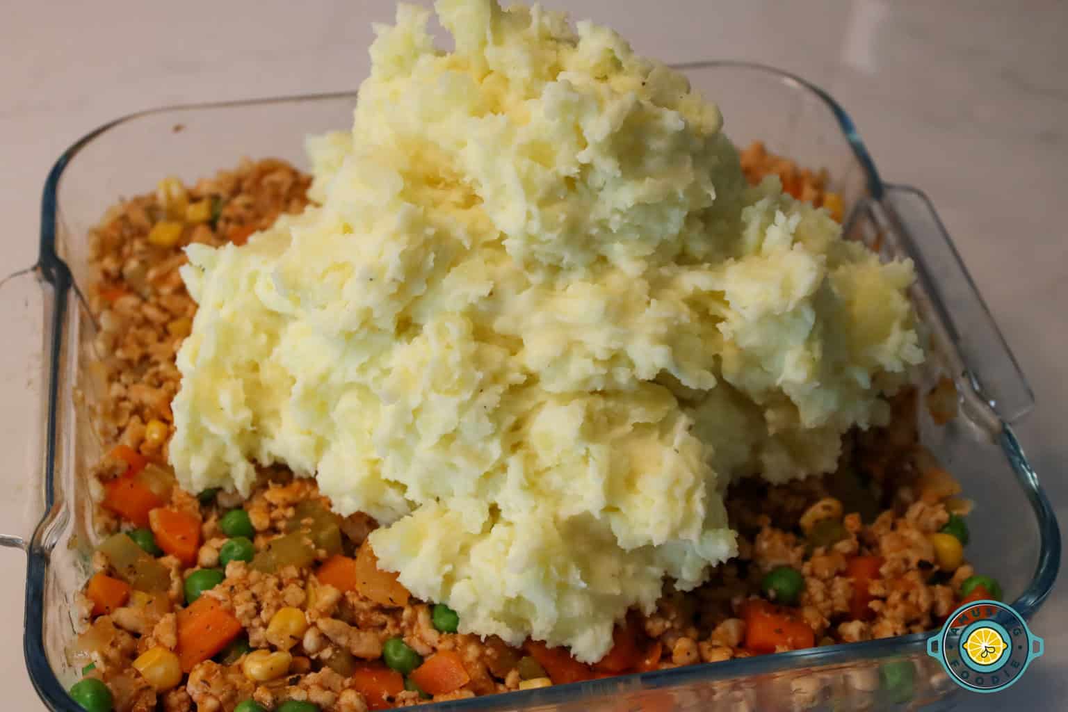 Adding mashed potato on top of ground turkey mixture